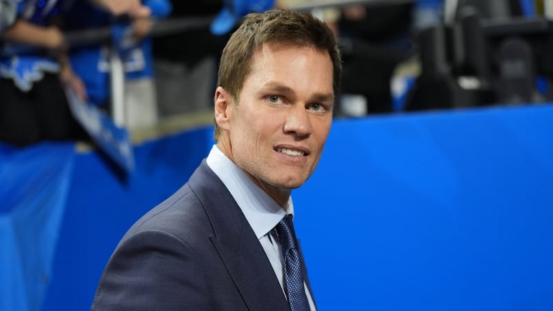 Former NFL player Tom Brady stands on the field before an NFL football game between the...