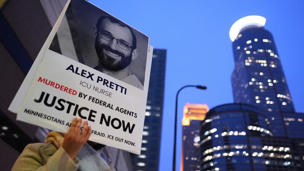 A person holds a sign of Alex Pretti during a protest outside the office of Sen. Amy...