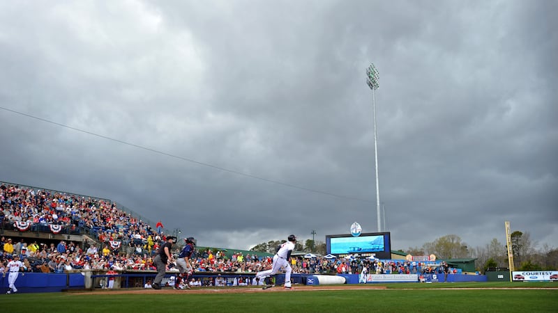 Atlanta Braves' Freddie Freeman runs toward first base as rain clouds move in before a...