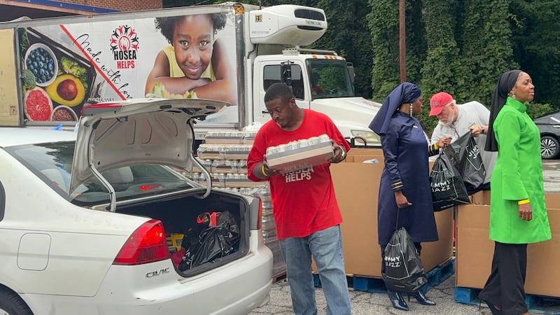 Volunteers place food, drinks and school supplies in cars as families lined up to receive help